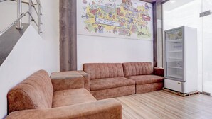 Una sala de estar moderna con un conjunto de sofás, piso de madera, un refrigerador y un mapa mural.