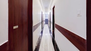 A hotel hallway with a wooden door, a marble floor, and a staircase at the end. - Hotel New Blue Sapphire Residency (Mumbai)