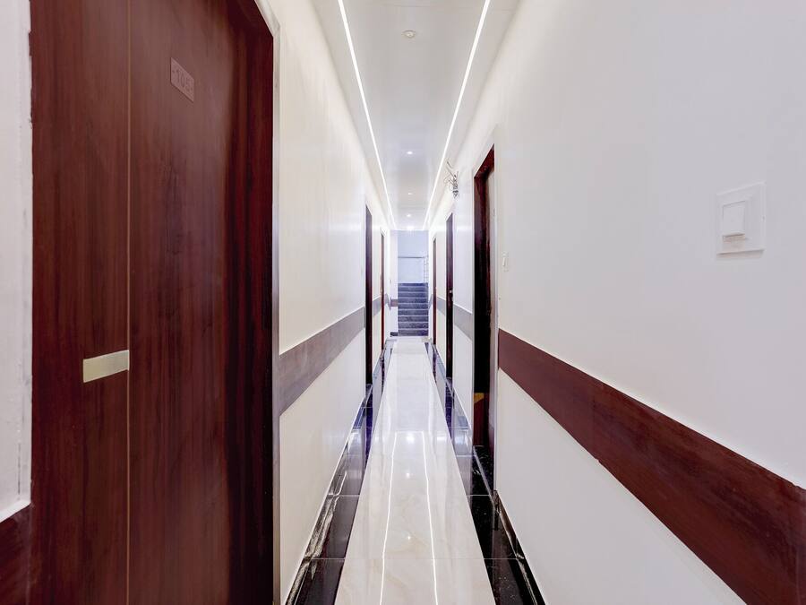 Un pasillo de hotel con puerta de madera, suelo de mármol y una escalera al final.