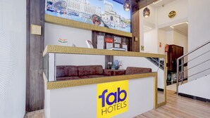 A reception area with a 'Tab Hotels' sign, a couch, a wall-mounted clock, and a staircase. - Hotel New Blue Sapphire Residency (Mumbai)