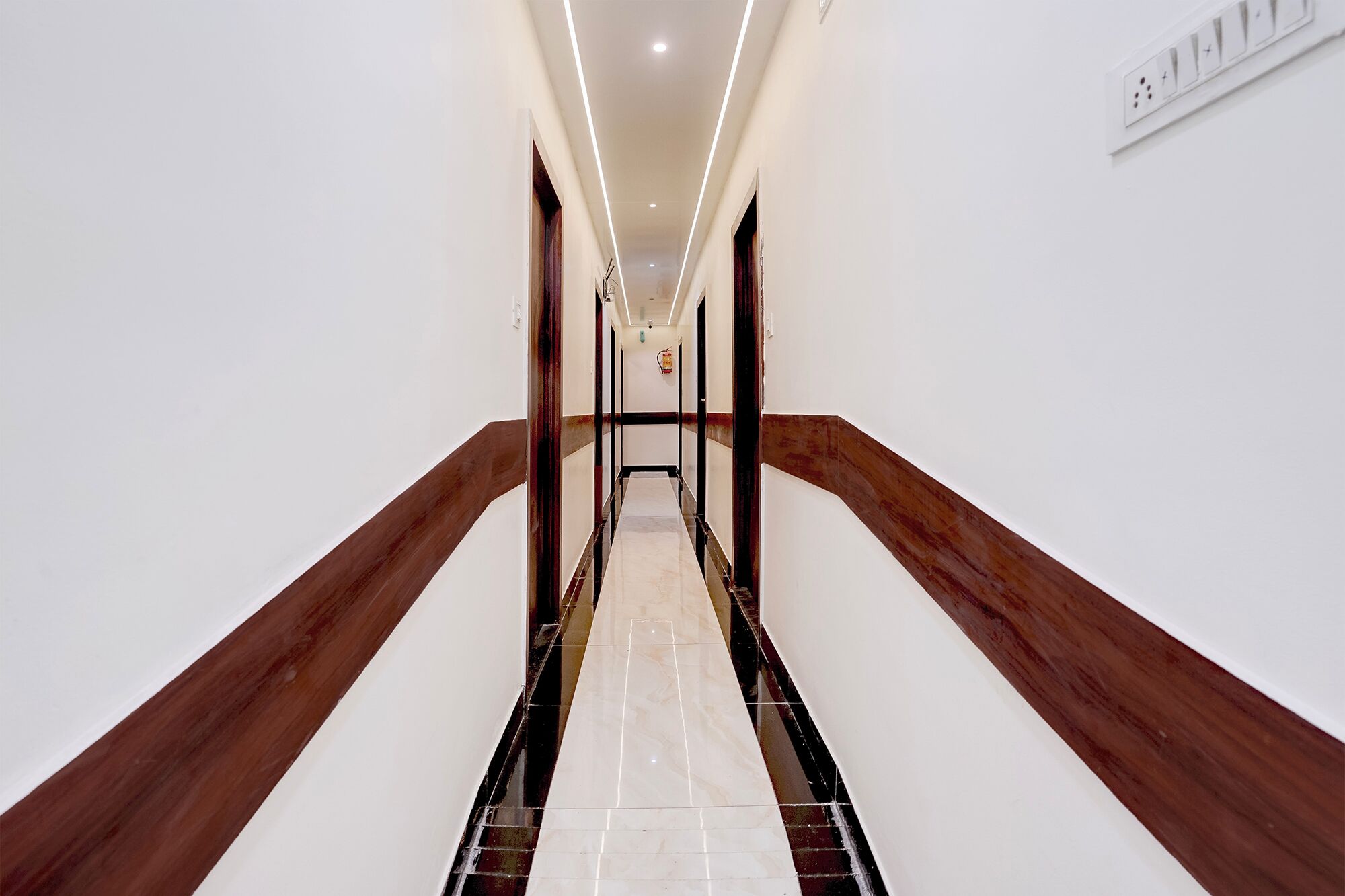 A hallway with a marble floor, wooden handrails, and recessed lighting.