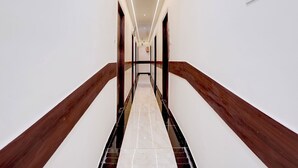 Un pasillo con piso de mármol, barandas de madera e iluminación empotrada.