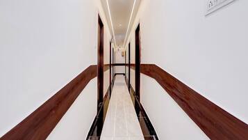 A hallway with a marble floor, wooden handrails, and recessed lighting.