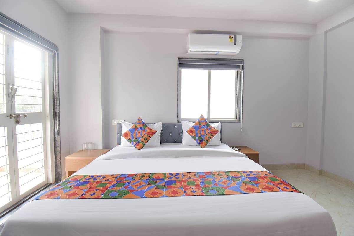 Habitación de hotel con cama, ventana, aire acondicionado y puerta.