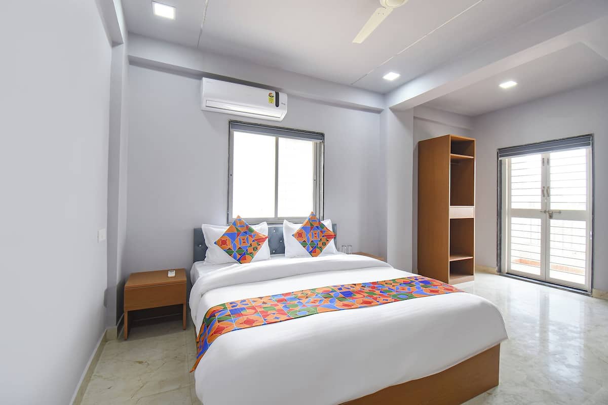 Un dormitorio moderno con cama, mesita de noche, armario y aire acondicionado.