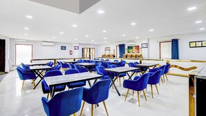 Un comedor amplio con mesas y sillas azules, unidades de aire acondicionado y obras de arte en las paredes.