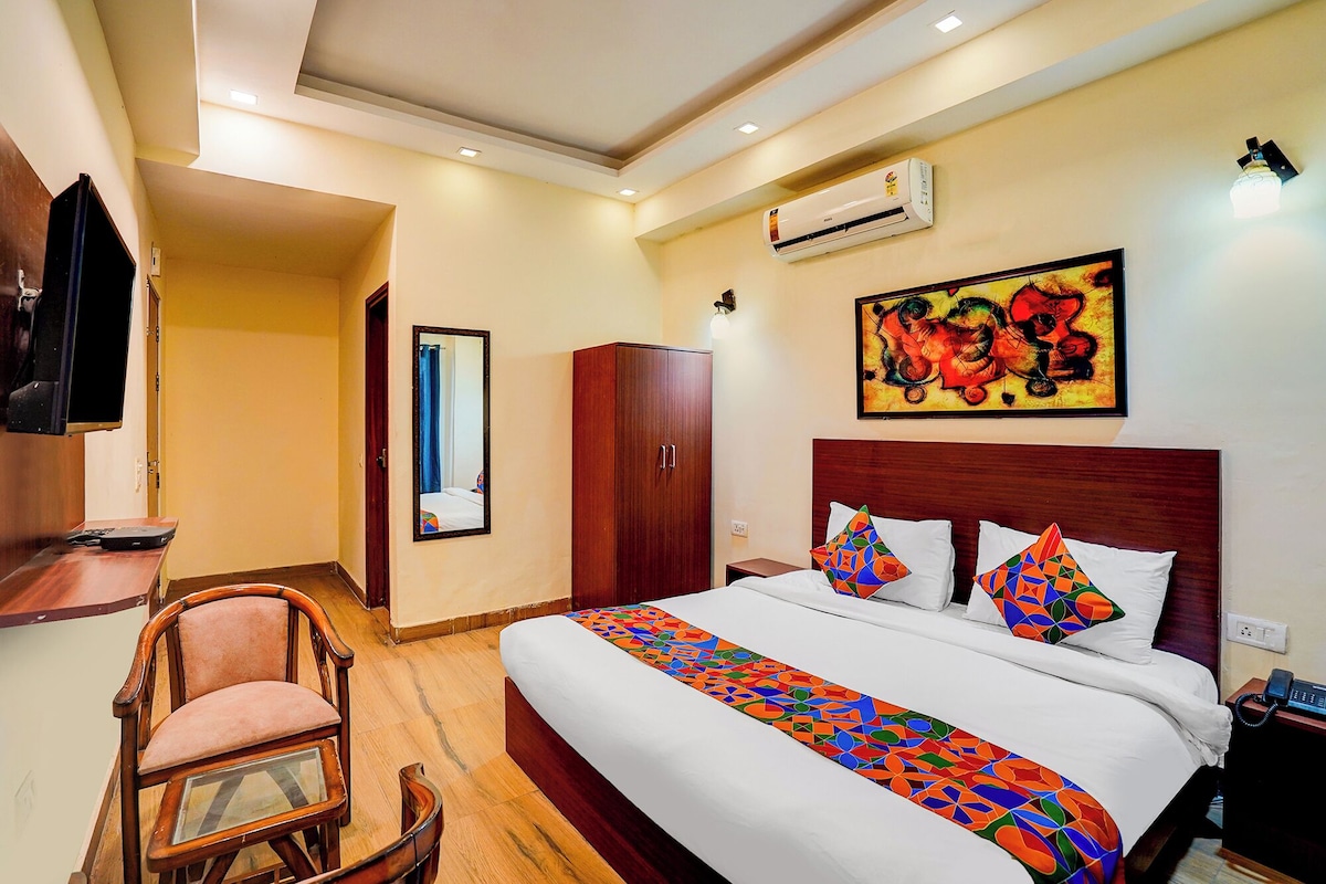 Quarto de hotel com cama, cadeira, guarda-roupa, ar condicionado, um quadro e telefone.