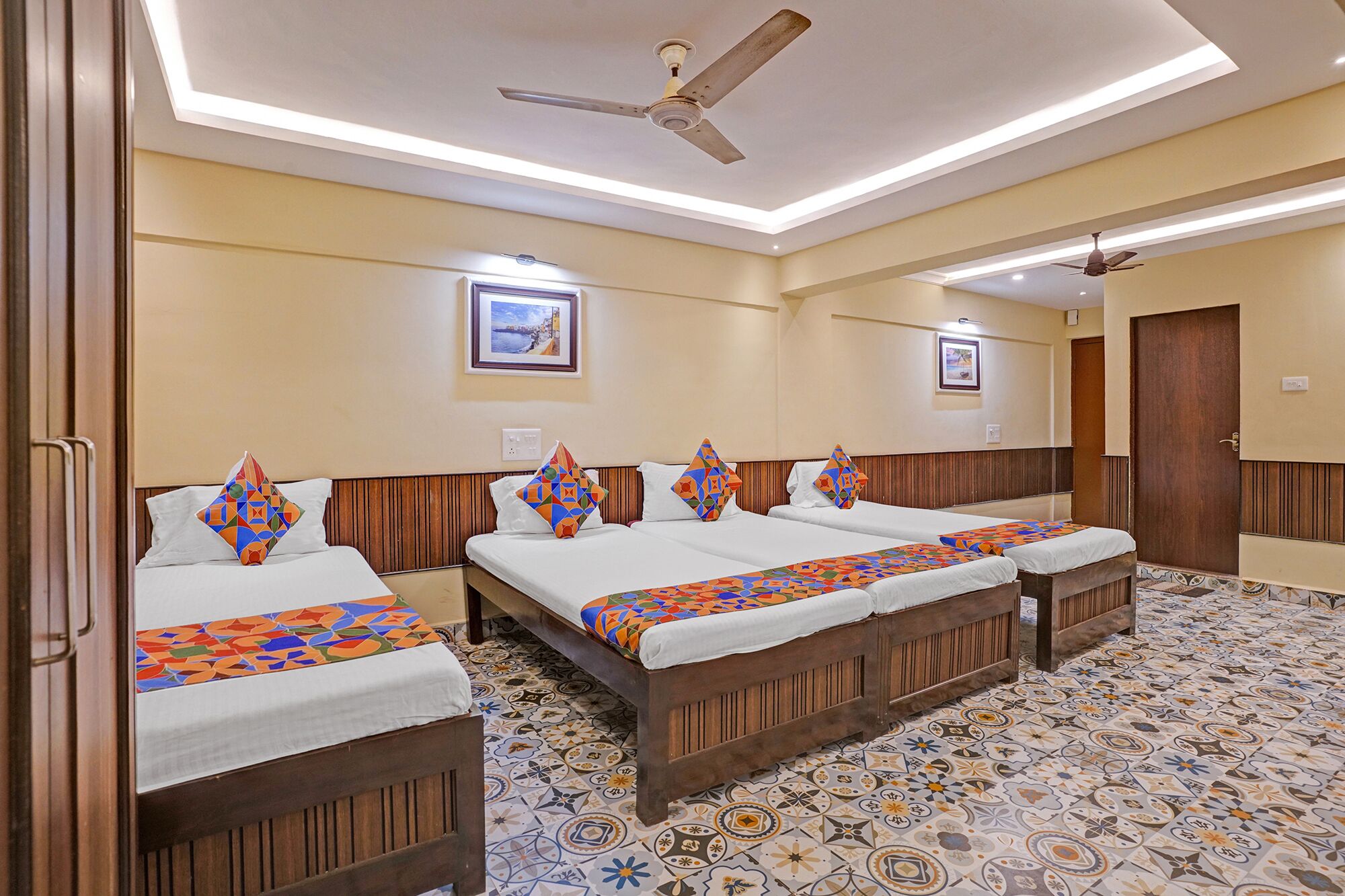 A hotel room with two beds, a ceiling fan, and a tiled floor.