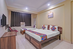 Habitación de hotel con dos camas, televisión, aire acondicionado y un cuadro en la pared.