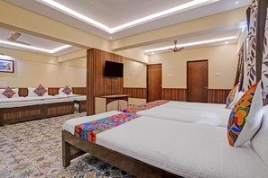 Quarto de hotel com duas camas, televisão e ventilador de teto.