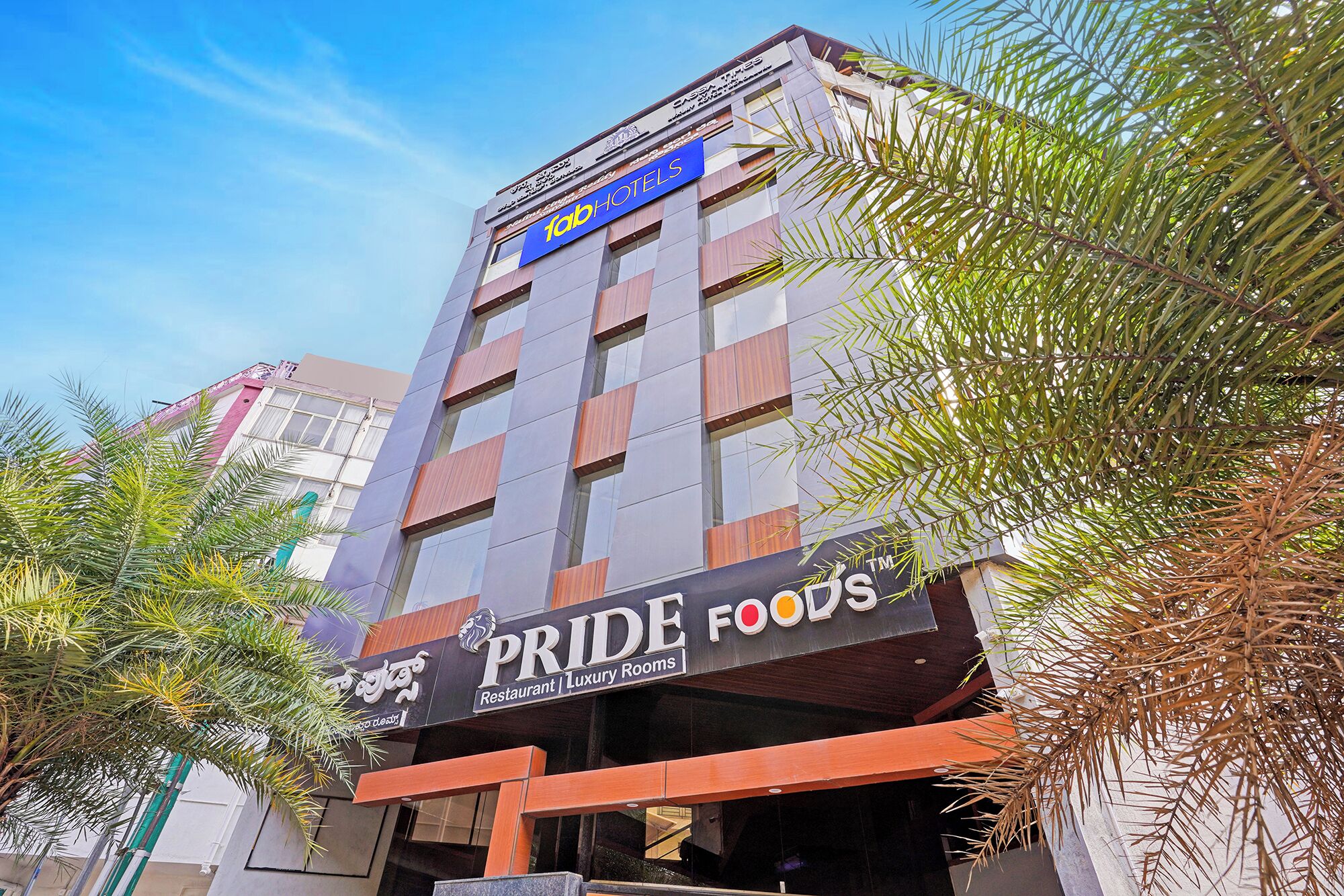 Un hotel con un cartel que dice 'fabHOTELS' y un restaurante llamado 'PRIDE FOODS', con habitaciones de lujo.