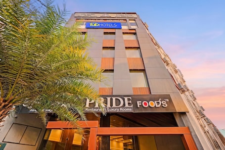 A building with a sign for 'fabHOTELS' and 'PRIDE FOODS Restaurant | Luxury Rooms' on the facade.. Fabhotel Pride