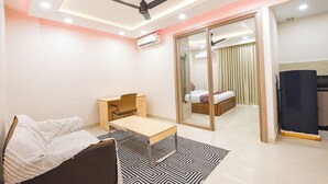 A modern bedroom with a bed, desk, chair, and a sliding door leading to a bathroom. - FabHotel Prime Hush & Suites - Manesar and Sector 86 (Gurugram)
