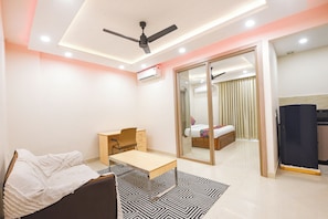 A modern bedroom with a bed, desk, chair, and a sliding door leading to a bathroom. - Fabhotel Prime Hush & Suites (Gurugram)