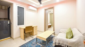 A bedroom with a desk, a bed, a ceiling fan, and an air conditioning unit. - FabHotel Prime Hush & Suites - Manesar and Sector 86 (Gurugram)
