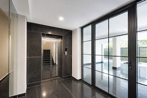 Ein modernes Interieur mit Glastür zum Balkon, einer Treppe und einer Deckenleuchte.