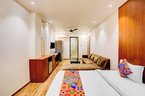 A hotel room with a bed, a desk, a TV, a ceiling fan, and a door. - FabHotel Prime Kartar Grand - Nr. Fazalganj Chauraha (Kanpur)