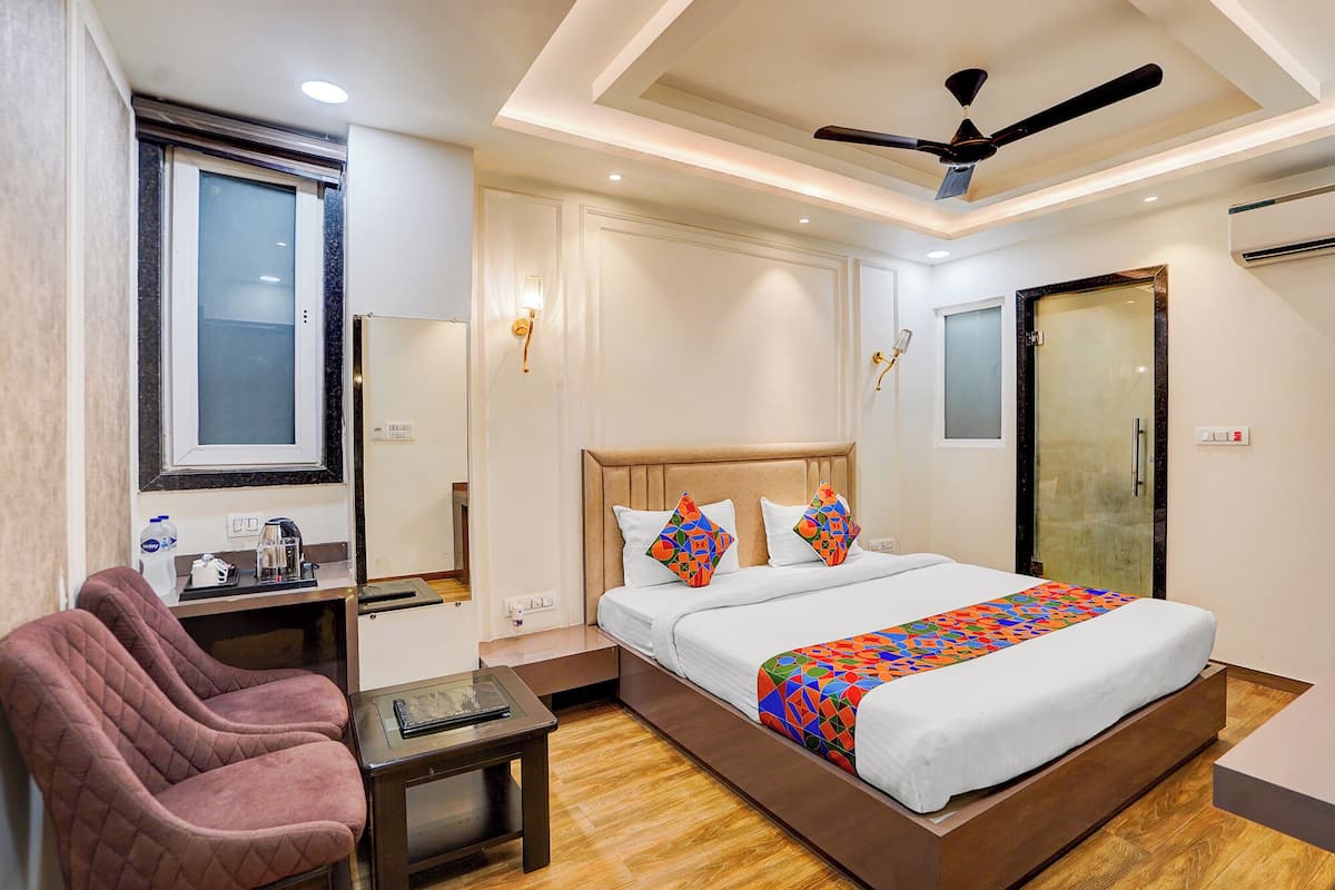 A hotel room with a bed, a desk, a chair, a ceiling fan, and a window.
