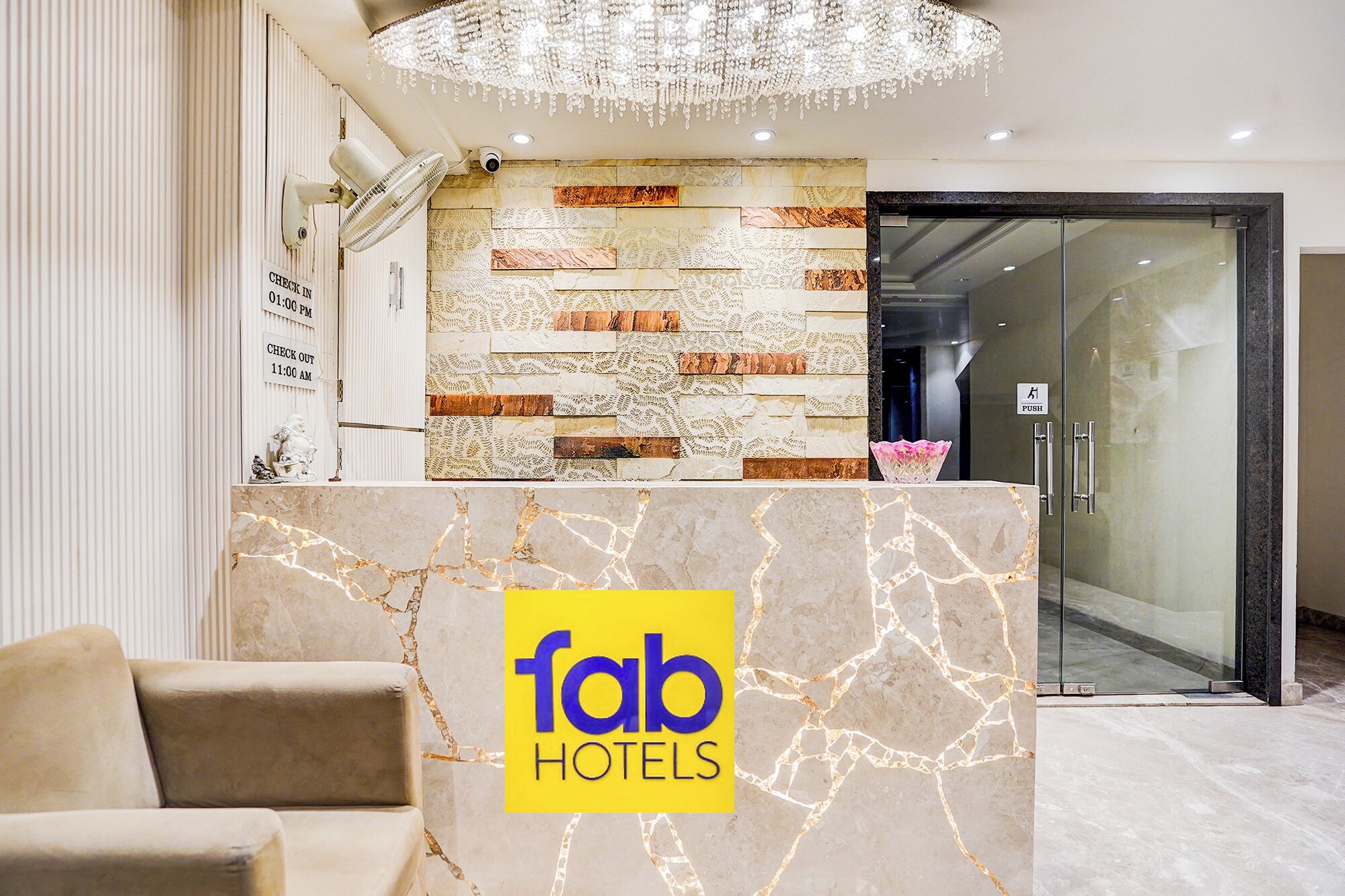 A hotel reception desk with a marble counter, a chandelier, and a 'fab hotels' logo.