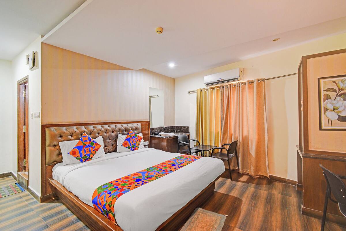 Habitación de hotel con cama, escritorio y zona de ducha.