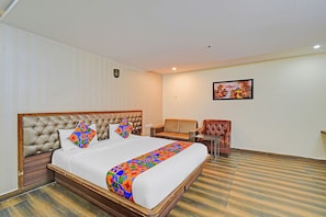 A hotel room with a large bed, a sofa, a chair, and a painting on the wall. - Fabhotel Prime Surabhi Elite (Hyderabad)
