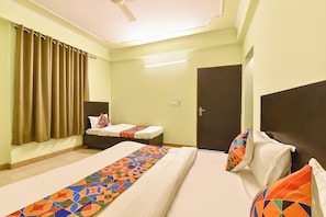 Habitación de hotel con dos camas, un ventilador de techo, una puerta y una ventana con cortinas.