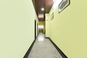 A hallway with light green walls, a black and white speckled floor, and a framed picture on the wall.