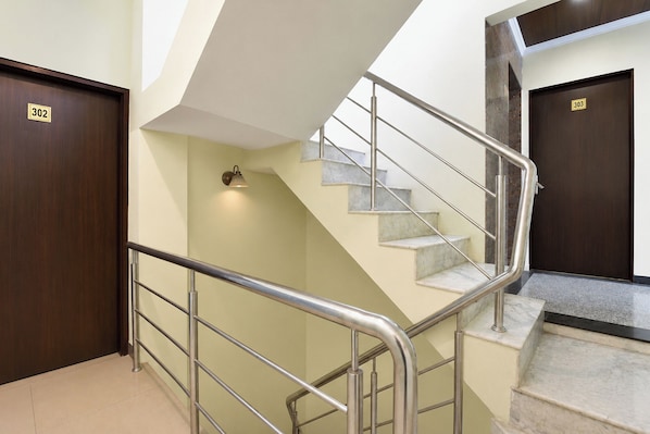 A staircase with metal railings, a wall-mounted light, and two doors labeled '302' and '303'.