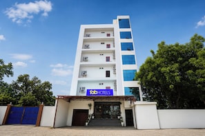 Un hotel de varios pisos con un letrero azul que dice 'fab hotels' en la entrada.