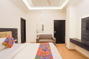A modern hotel room with a bed, a sofa, a TV, and a ceiling light. - Fabhotel Roomers (Varanasi)
