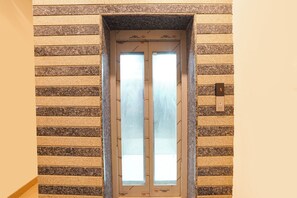 An elevator with a digital display showing the number 5, surrounded by a wall with a patterned design. - Fabhotel Roomers (Varanasi)
