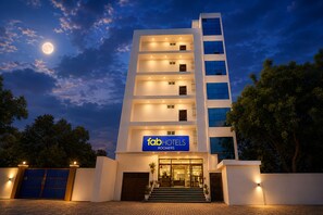 A multi-story building with a sign for 'fabHOTELS ROOMERS' and a moon in the sky. - Fabhotel Roomers (Varanasi)
