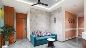Un interior modern amb un sofà color cel, una taula rodona, un ventilador de sostre i una paret amb cites motivadores.