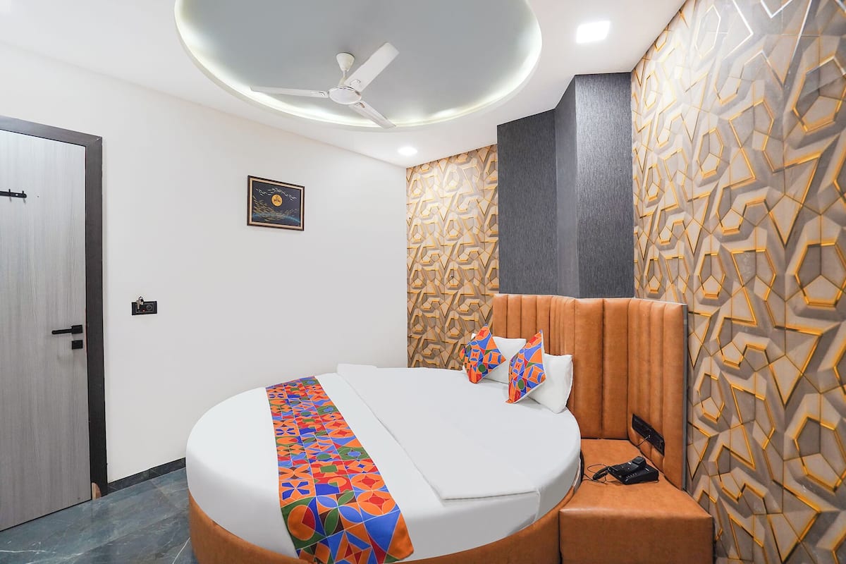 A modern hotel room with a round bed, a ceiling fan, geometric wall decor, and a door with a handle.