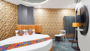 Habitació d'hotel moderna amb un llit gran, un televisor muntat a la paret, una taula petita i una cadira.