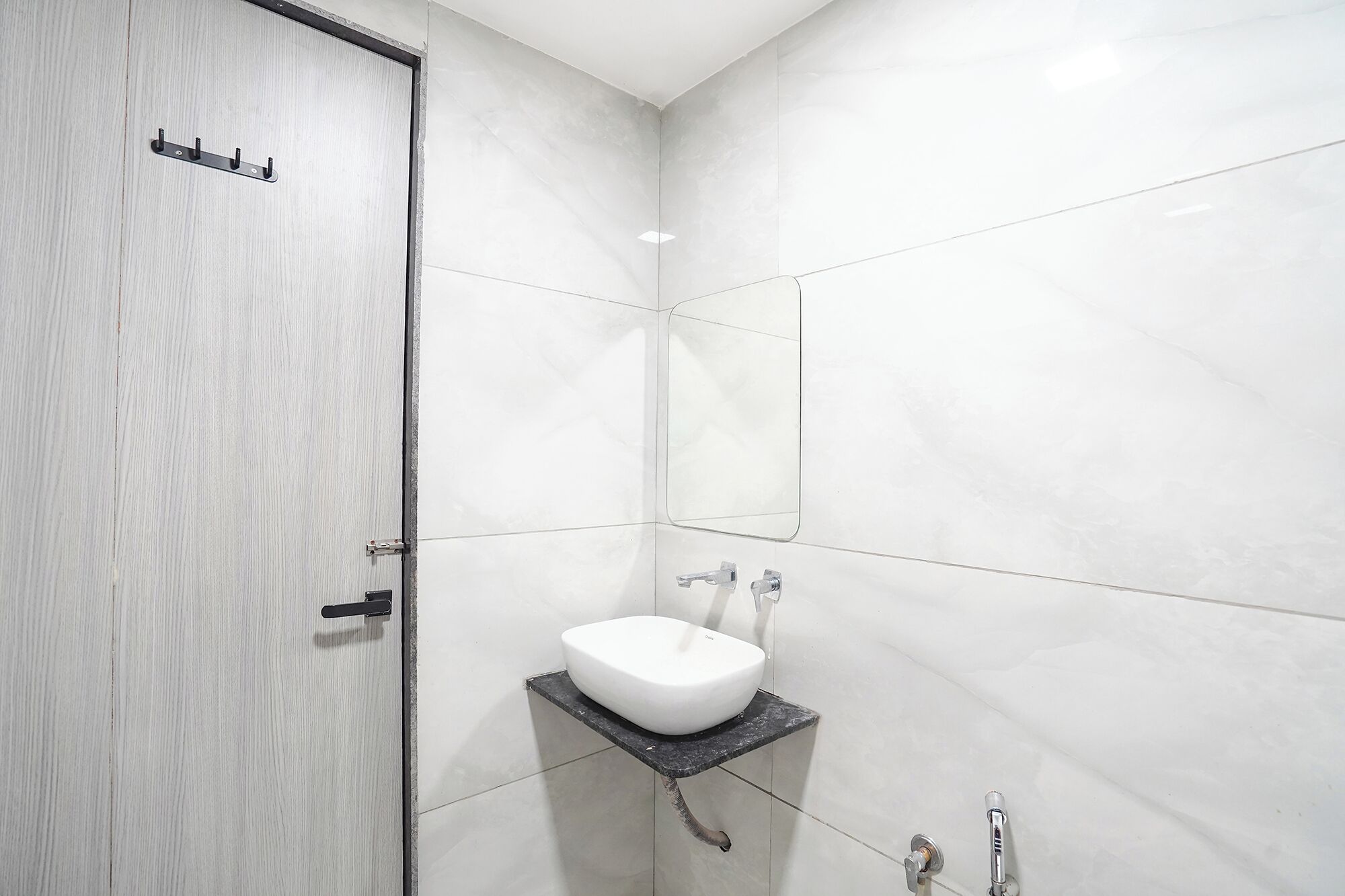 A bathroom with a white sink, a shower, and a door with a handle.