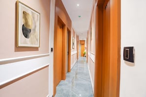 Ein Hotelgang mit Holztüren, einem gerahmten abstrakten Kunstwerk und einem Marmorboden.