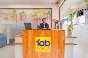 A reception desk with a 'fab hotels' sign, a laptop, and a potted plant.
