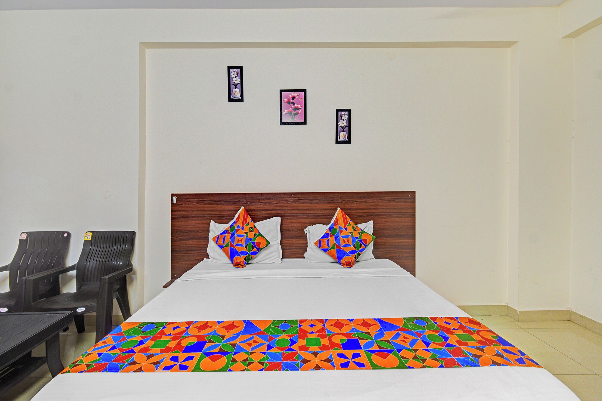 Habitación de hotel con cama, dos almohadas, cabecero y tres cuadros en la pared.