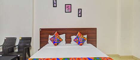 Habitación de hotel con cama, dos almohadas, cabecero y tres cuadros en la pared.