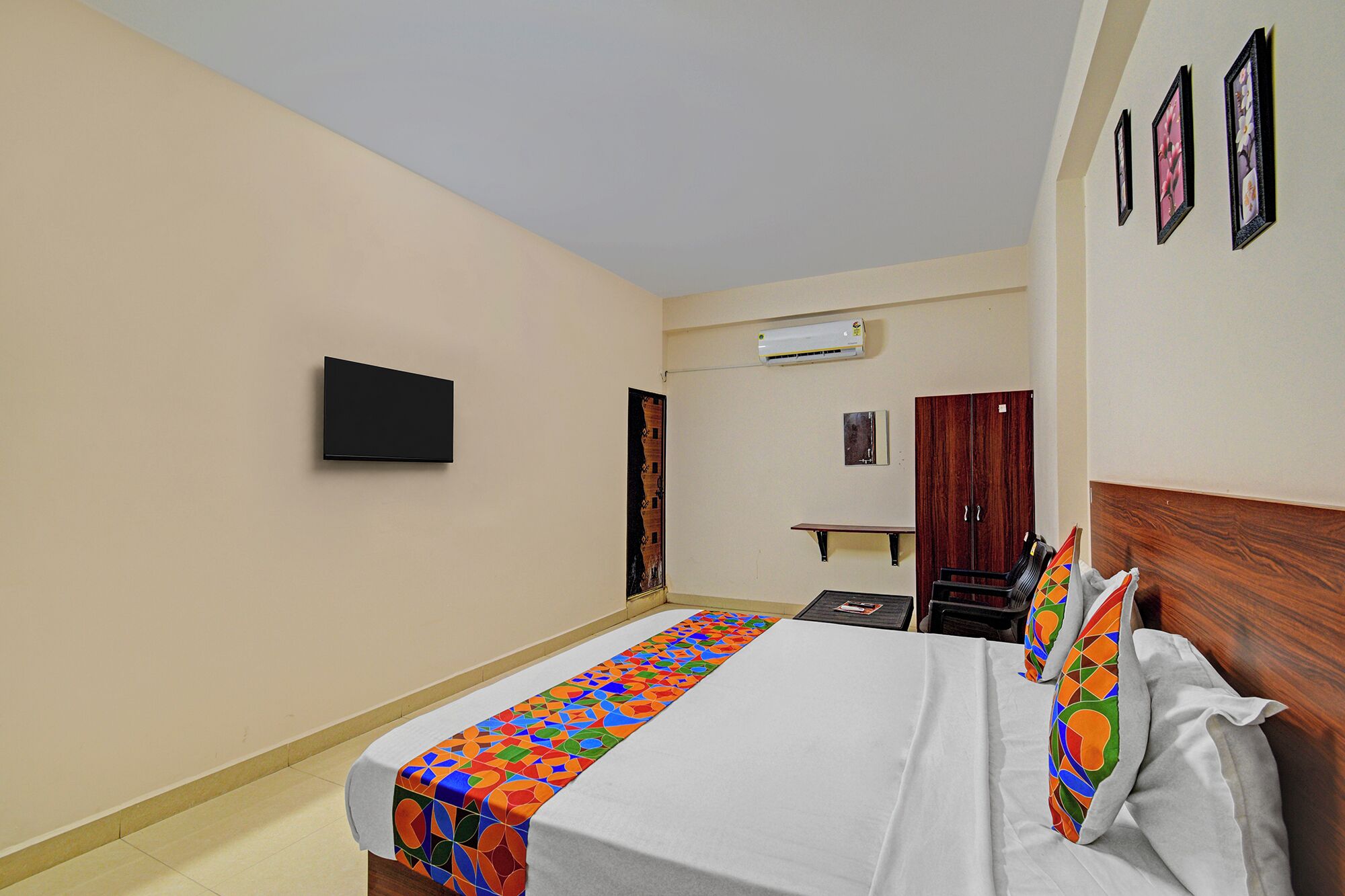Quarto de hotel com cama, televisão de tela plana, ar condicionado, guarda-roupa e uma mesa pequena.
