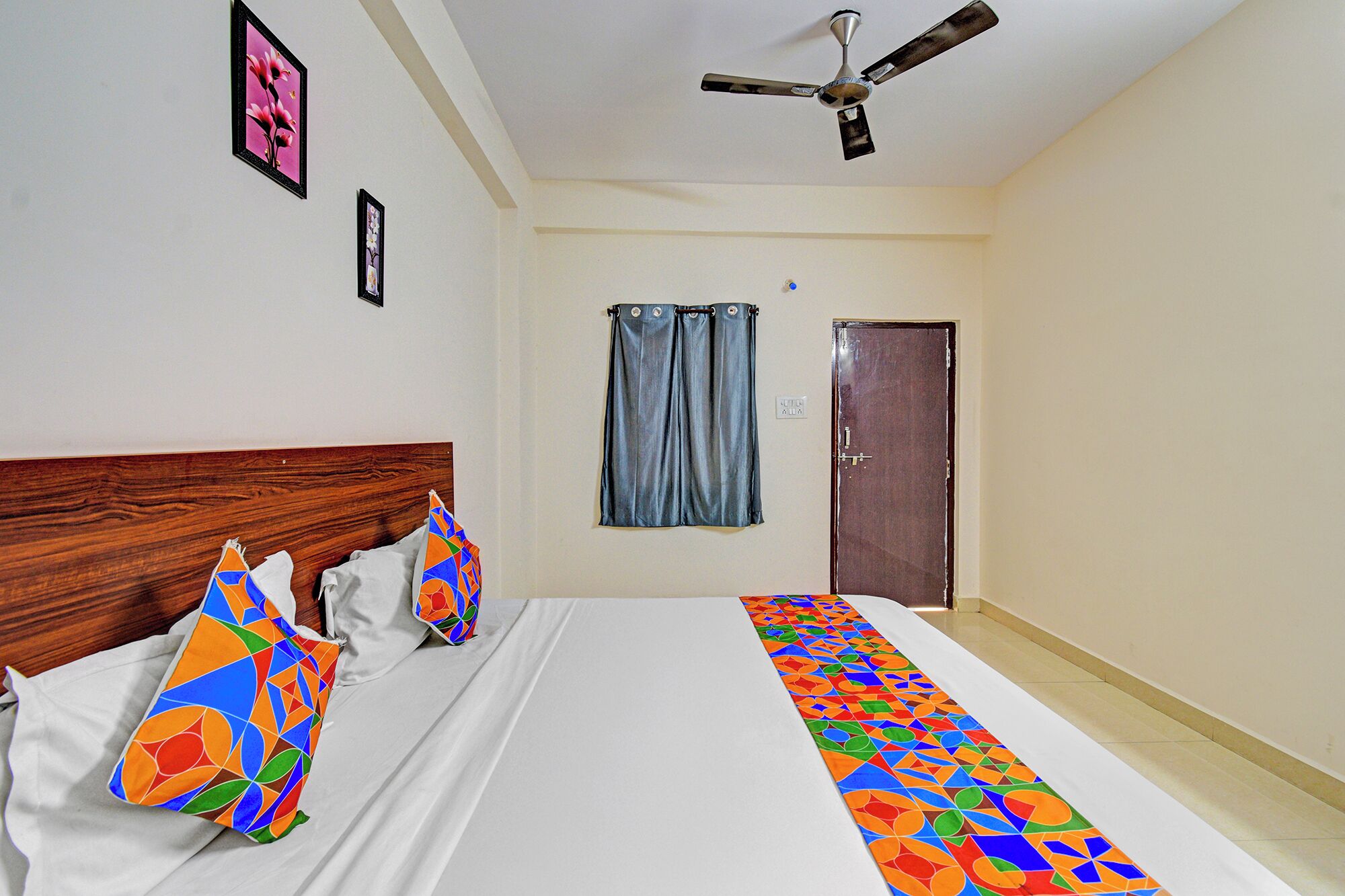 A bedroom with a bed, a ceiling fan, a door, and a window with curtains.