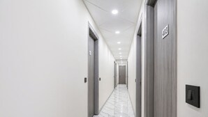 Un pasillo con puertas identificadas con los números 402 y 403, suelo de mármol e iluminación empotrada en el techo.