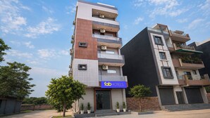 Un hotel de varios pisos con diseño moderno, que cuenta con balcones, unidades de aire acondicionado y un cartel de hotel visible.