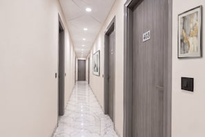 Um corredor com piso de mármore, portas numeradas 403 e uma obra de arte emoldurada na parede.