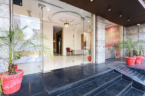 A hotel lobby with glass doors, a staircase, and potted plants. - Fabhotel Shree Priyasharnam (Vrindavan)