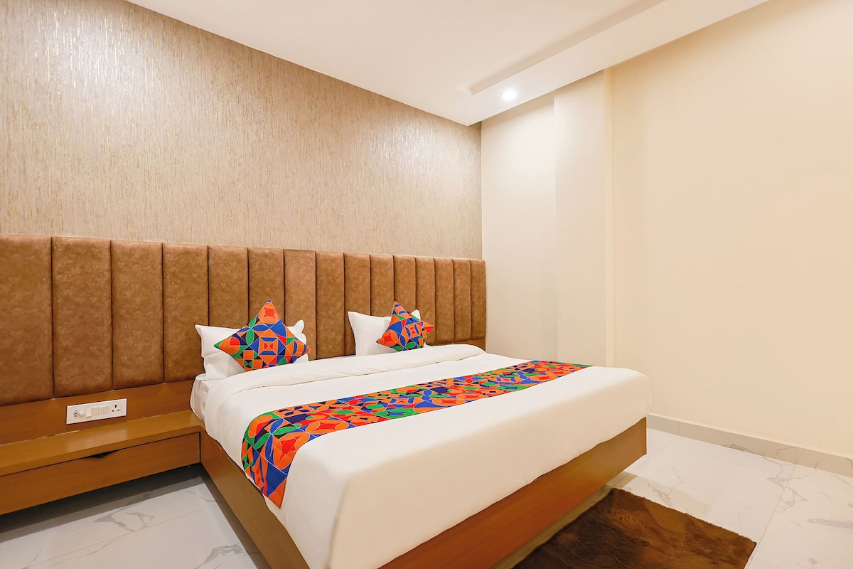 A hotel room with a bed, a nightstand, a wall with a textured finish, and a light switch.