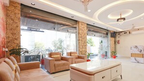 En moderne hotellobby med lædersofaer, en receptionsdisk i marmor og store vinduer med udsigt over byen.