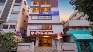 En byggnad med flera våningar, med en framträdande skylt för hotellet ”SITARA GRAND”.