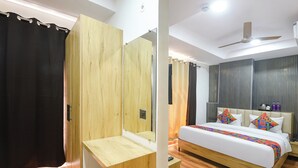A modern bedroom with a bed, a wooden desk, a mirror, and a ceiling fan. - Fabhotel Sky Inn (New Delhi)